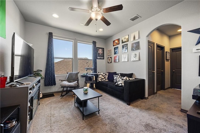 carpeted living area with arched walkways, visible vents, recessed lighting, and ceiling fan