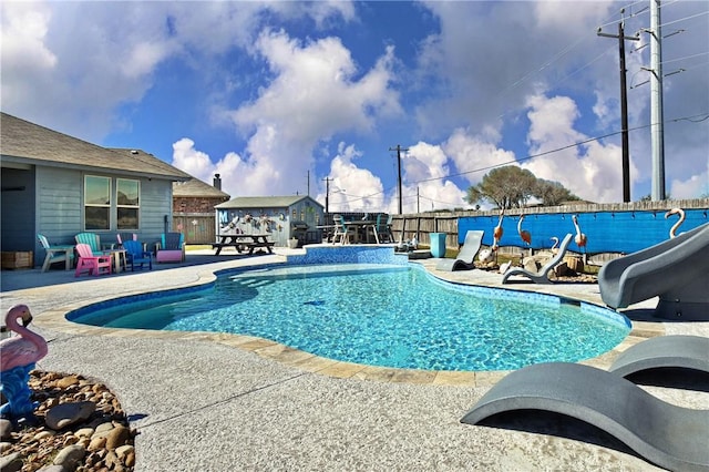 view of swimming pool featuring a patio area, a fenced in pool, a water slide, and fence