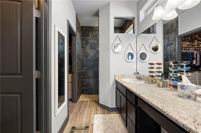 full bathroom featuring vanity, wood finished floors, and baseboards