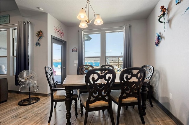 dining area featuring wood finish floors, baseboards, and a notable chandelier