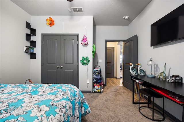 carpeted bedroom featuring visible vents, a textured ceiling, and a closet