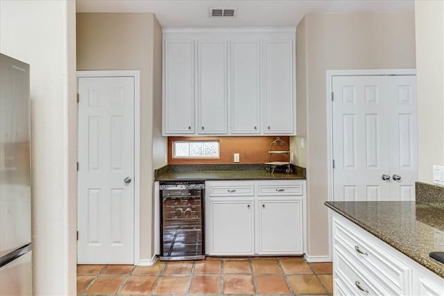 13530 Royal Fifth Ct, Corpus Christi, TX 78418 - kitchen with wine cooler, white cabinets, freestanding refrigerator, dark stone countertops, and light tile patterned floors