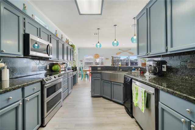 kitchen featuring appliances with stainless steel finishes, decorative light fixtures, tasteful backsplash, and light hardwood / wood-style floors