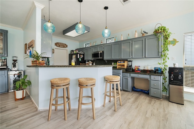 kitchen featuring kitchen peninsula, dark stone counters, light hardwood / wood-style floors, black refrigerator, and ornamental molding