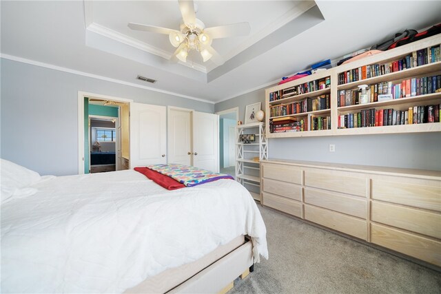 bedroom with light carpet, a tray ceiling, ceiling fan, and ornamental molding