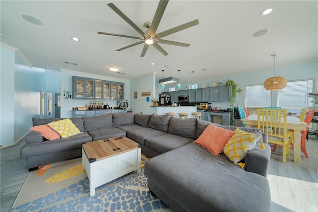 living room with ceiling fan, light wood-type flooring, and ornamental molding