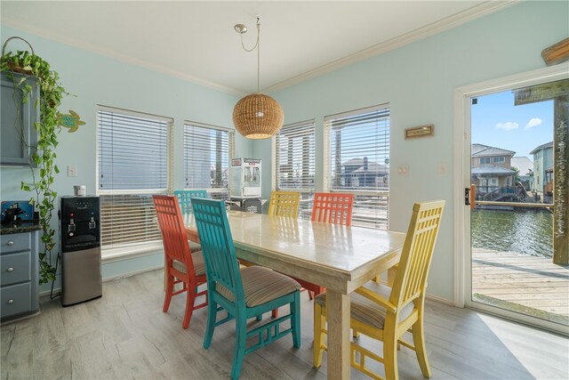 dining room with a water view, light wood-type flooring, and crown molding