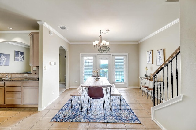 tiled dining area featuring sink, ornamental molding, and a chandelier