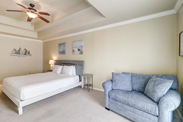 carpeted bedroom with ceiling fan, a tray ceiling, and ornamental molding