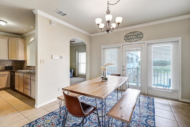 dining area with light tile patterned floors, sink, crown molding, and a chandelier