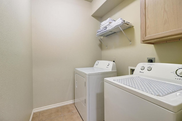 laundry area with light tile patterned floors, washing machine and dryer, and cabinets