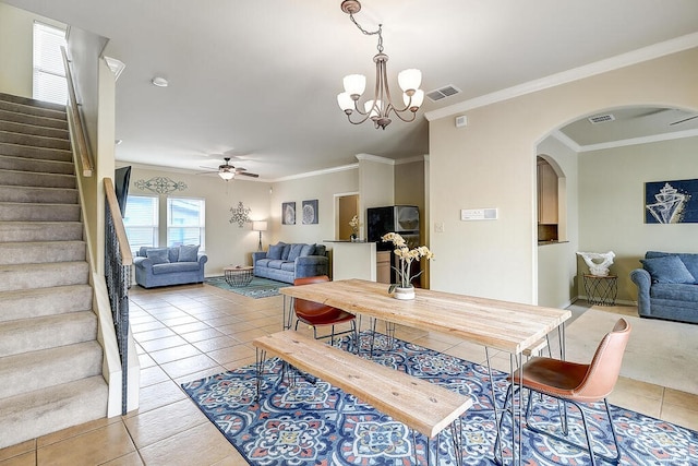 dining area with light tile patterned flooring, ceiling fan with notable chandelier, and ornamental molding