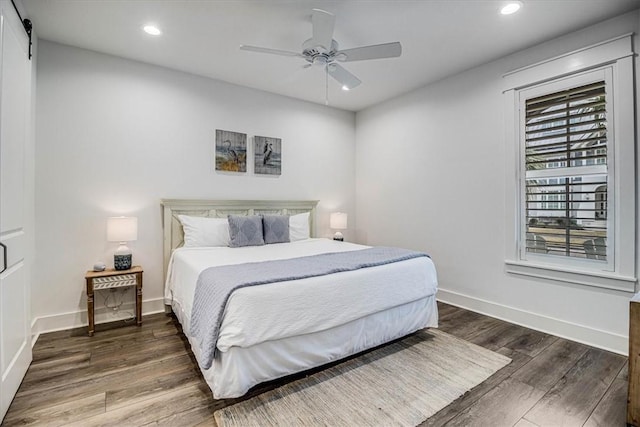 bedroom with dark wood-type flooring, recessed lighting, baseboards, and a barn door