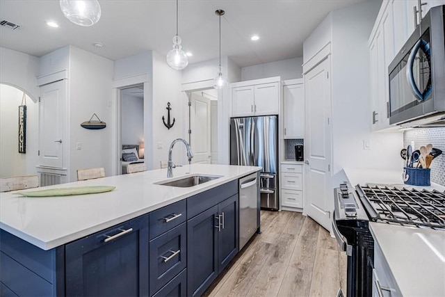 kitchen with white cabinets, hanging light fixtures, stainless steel appliances, light countertops, and a sink