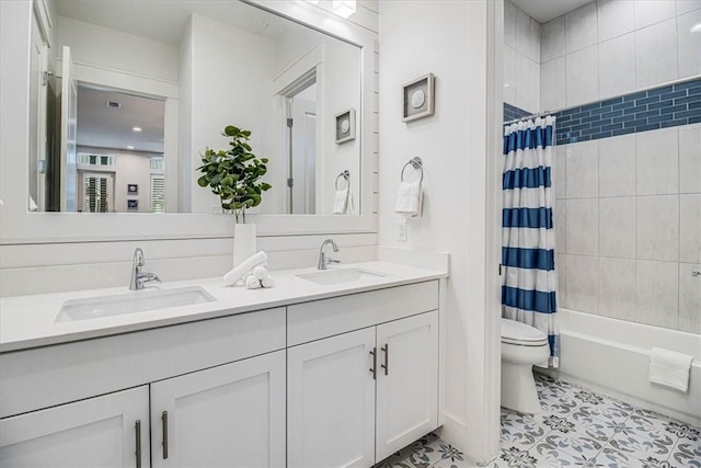 full bathroom featuring double vanity, shower / bath combination with curtain, toilet, and a sink