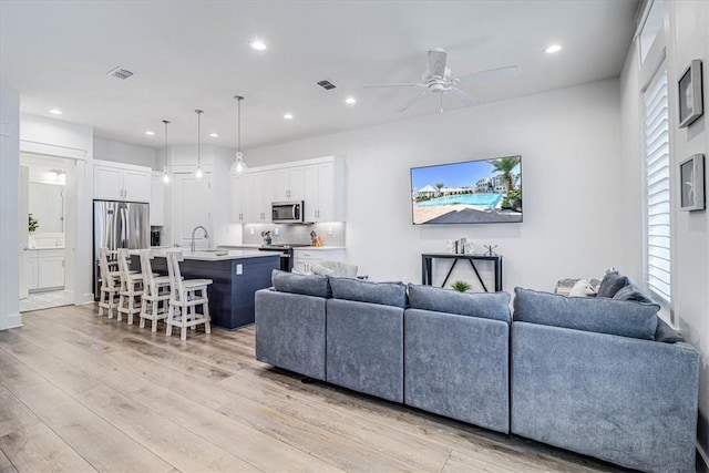 living room featuring ceiling fan, recessed lighting, visible vents, and light wood-style floors