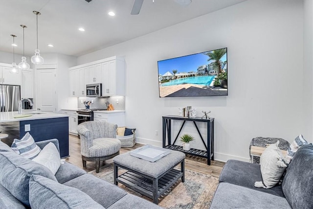 living area with ceiling fan, recessed lighting, light wood-style flooring, and baseboards