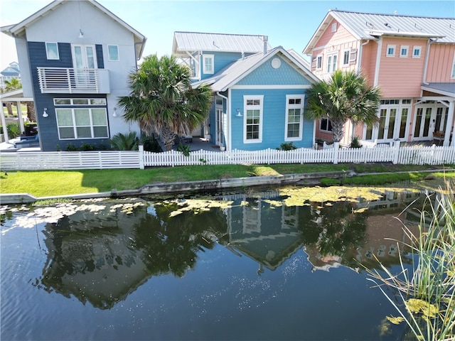 back of house with a water view and a lawn