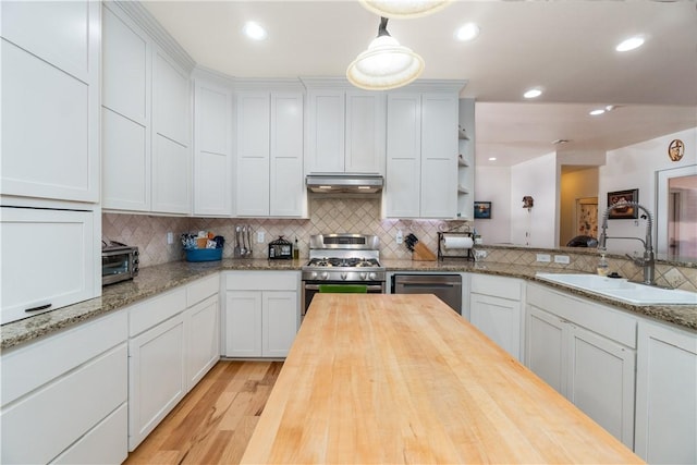 kitchen with appliances with stainless steel finishes, a sink, decorative light fixtures, and white cabinets