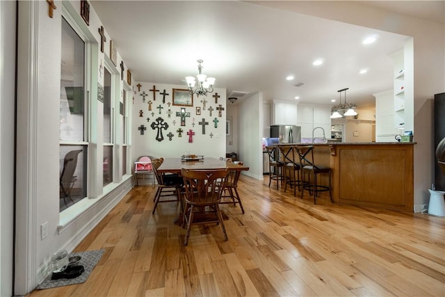 dining area with a chandelier, recessed lighting, and light wood-style flooring