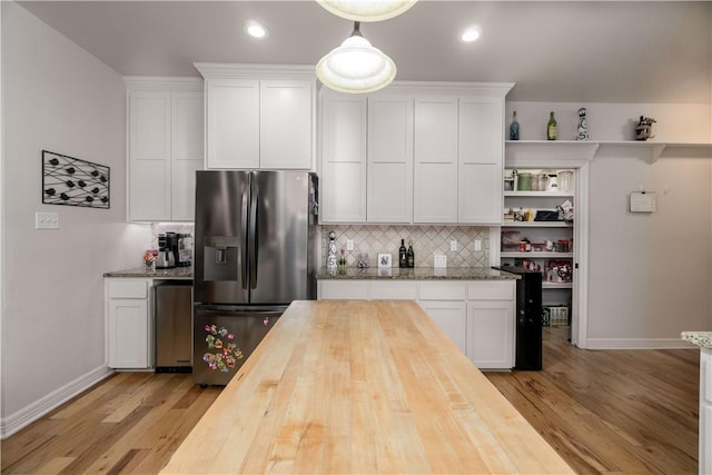 kitchen featuring pendant lighting, butcher block counters, white cabinetry, and stainless steel refrigerator with ice dispenser