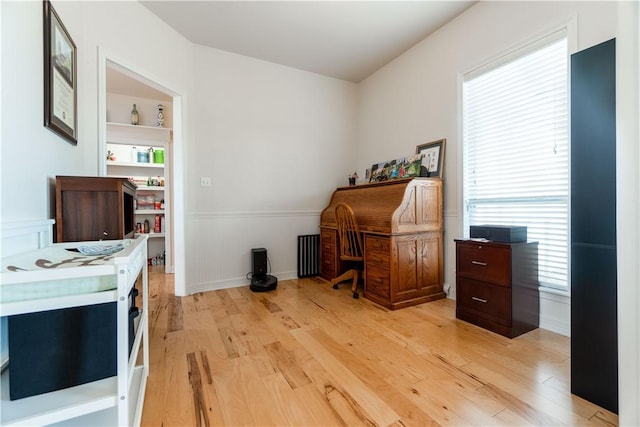 home office featuring wainscoting, light wood-type flooring, and a wealth of natural light