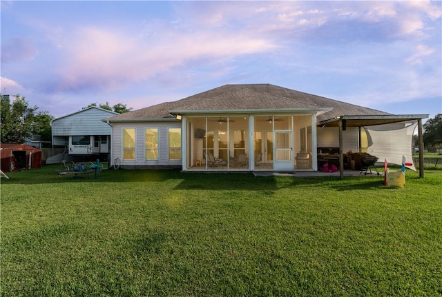 rear view of house featuring a patio, a lawn, and a sunroom