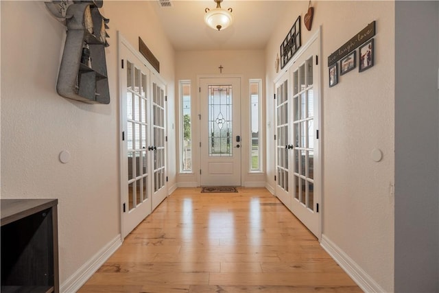 entrance foyer featuring light wood-style floors, visible vents, baseboards, and french doors