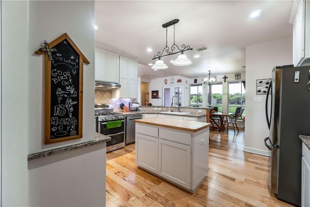 kitchen with stainless steel appliances, a peninsula, a sink, and white cabinets