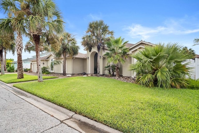 122 Bay Ct, Aransas Pass, TX 78336 - view of front of house featuring stucco siding, a garage, a front yard, and driveway
