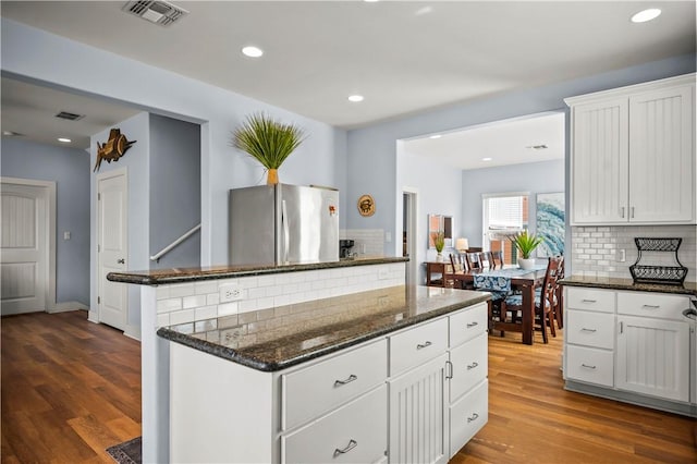 678 Anchor Dr, Port Aransas, TX 78373 - kitchen featuring freestanding refrigerator, backsplash, dark stone counters, dark wood finished floors, and white cabinetry