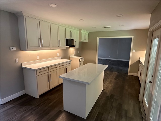 kitchen featuring white cabinetry, light stone counters, dark hardwood / wood-style floors, and a center island