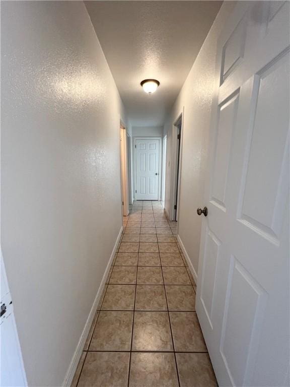 corridor with light tile patterned flooring and baseboards