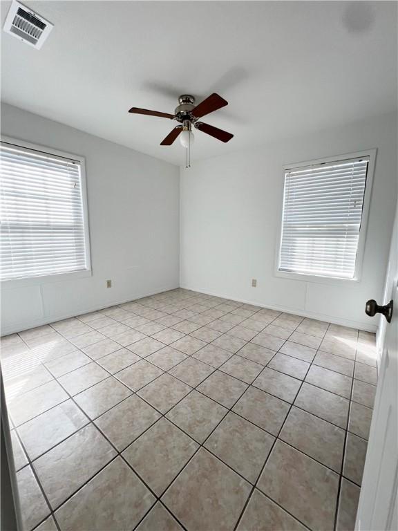 unfurnished room with light tile patterned floors, visible vents, and ceiling fan