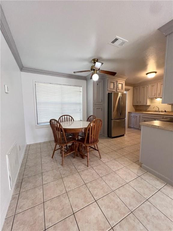 dining area featuring light tile patterned floors, visible vents, ornamental molding, and a ceiling fan