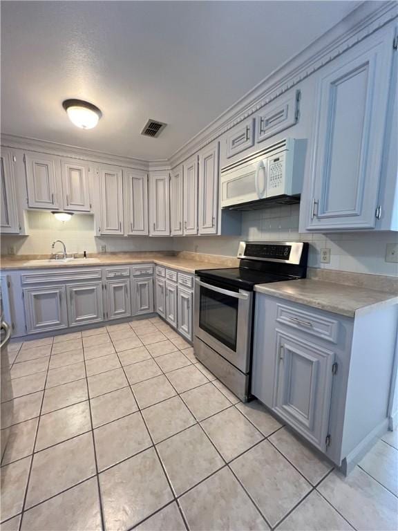 kitchen with electric range, visible vents, light tile patterned flooring, light countertops, and white microwave