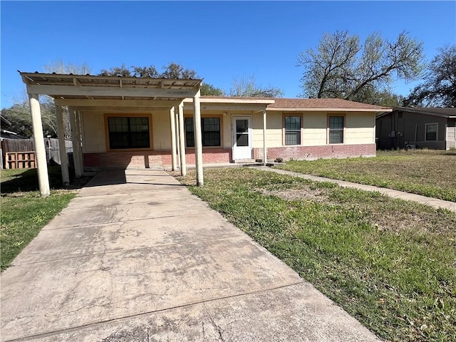 ranch-style home with a front lawn, driveway, a carport, fence, and brick siding