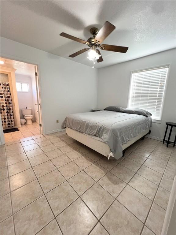 bedroom featuring light tile patterned floors, a textured ceiling, a ceiling fan, and baseboards