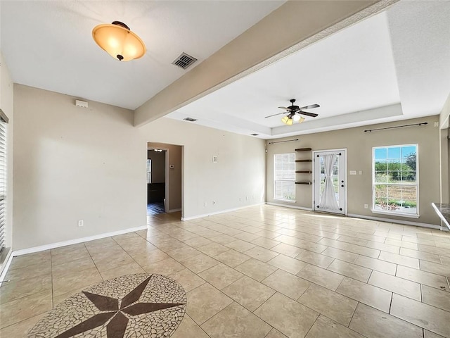 tiled spare room with beam ceiling, a tray ceiling, and ceiling fan