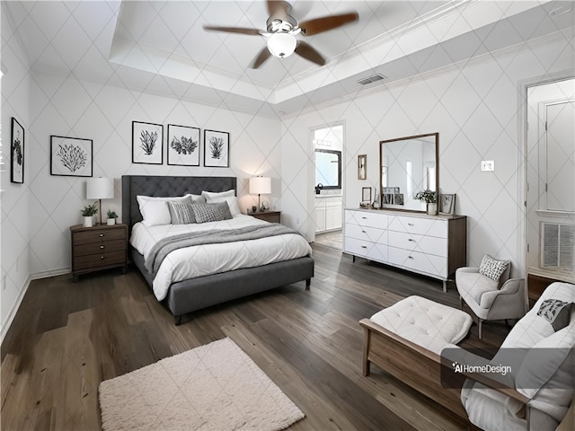 bedroom with dark wood-type flooring, ensuite bathroom, ceiling fan, and a raised ceiling