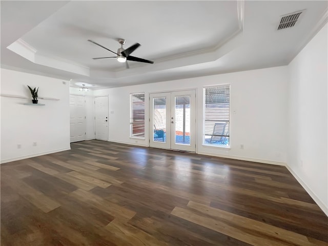 unfurnished room with ornamental molding, ceiling fan, a tray ceiling, dark wood-type flooring, and french doors