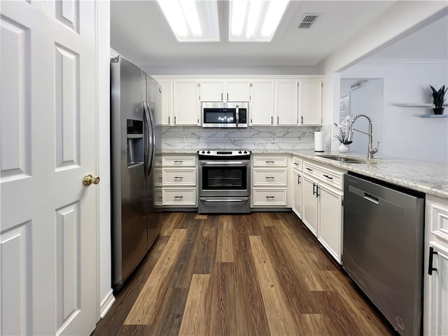 kitchen with sink, appliances with stainless steel finishes, backsplash, white cabinets, and dark hardwood / wood-style flooring