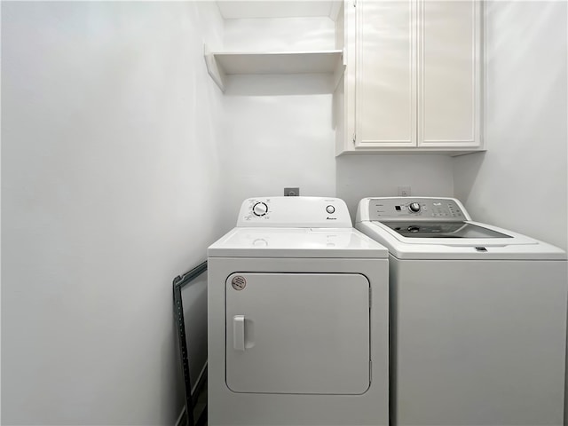 clothes washing area with cabinets and independent washer and dryer