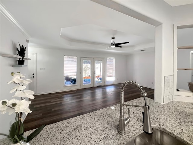 interior space featuring dark wood-type flooring, french doors, light stone counters, and a tray ceiling