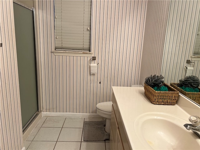 bathroom featuring toilet, vanity, tile patterned flooring, and a shower with shower door