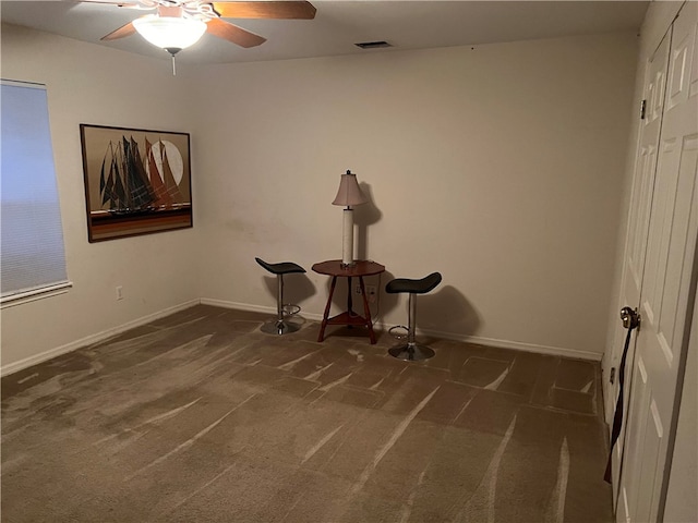 misc room with ceiling fan and dark colored carpet