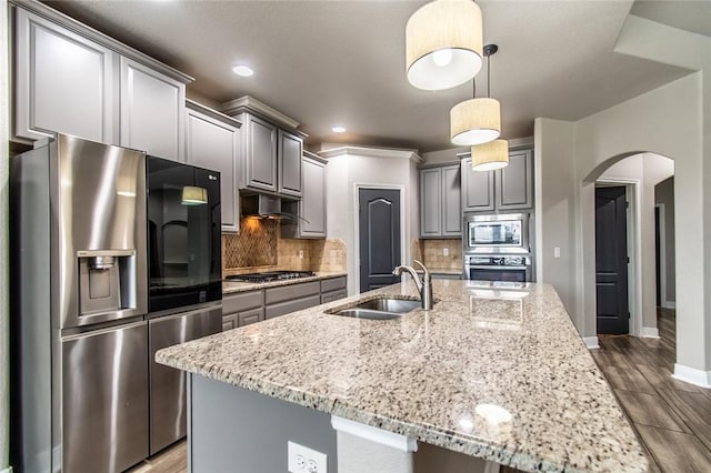 8022 Calgary Dr, Corpus Christi, TX 78414 - kitchen featuring appliances with stainless steel finishes, gray cabinetry, arched walkways, light stone countertops, and under cabinet range hood