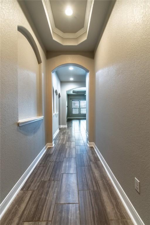8022 Calgary Dr, Corpus Christi, TX 78414 - hall featuring a textured wall, arched walkways, a tray ceiling, dark wood finished floors, and ornamental molding