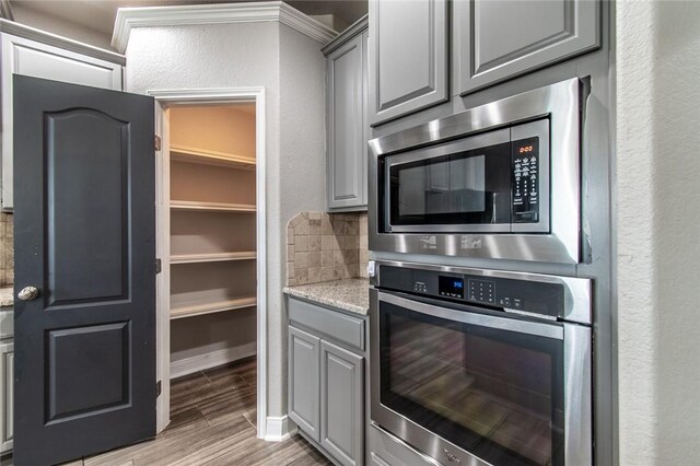 8022 Calgary Dr, Corpus Christi, TX 78414 - kitchen with stainless steel appliances, gray cabinets, tasteful backsplash, light wood-type flooring, and a textured wall