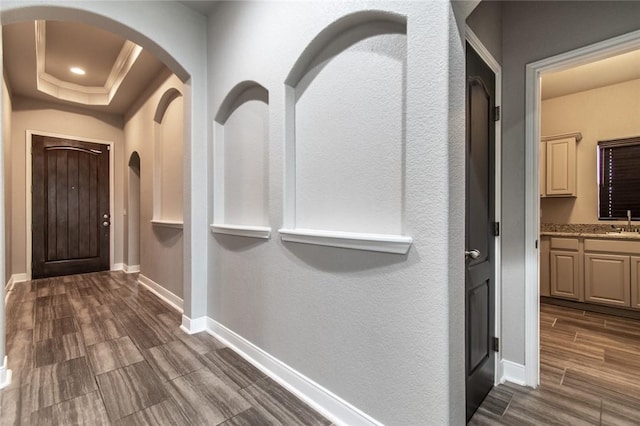 8022 Calgary Dr, Corpus Christi, TX 78414 - hall featuring arched walkways, dark wood-type flooring, and a tray ceiling